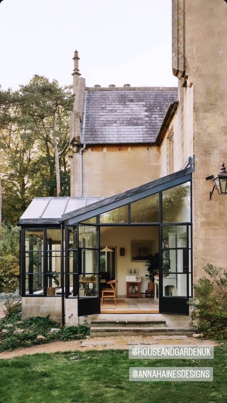 a large house with an open patio and glass doors on the front door is surrounded by greenery