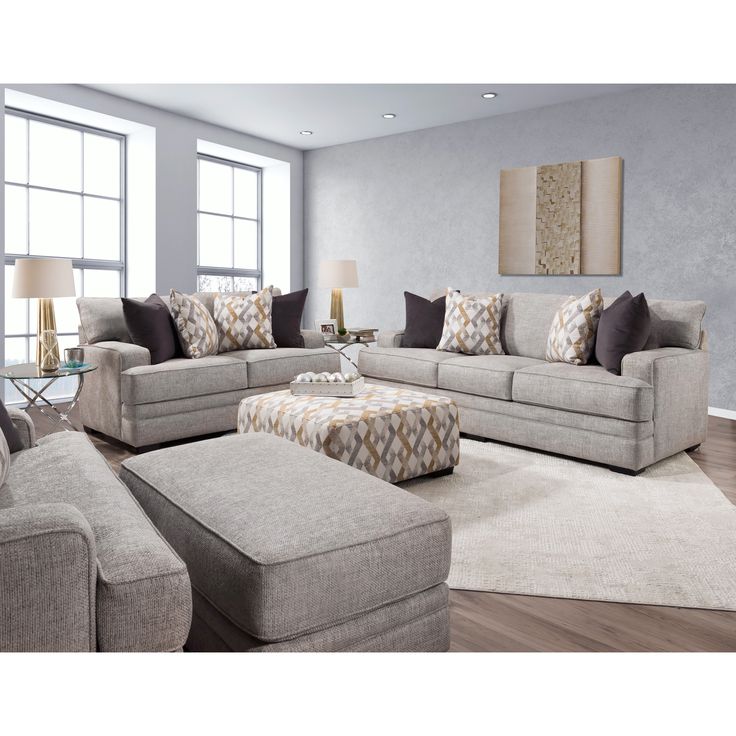 a living room with couches, chairs and ottomans in front of large windows