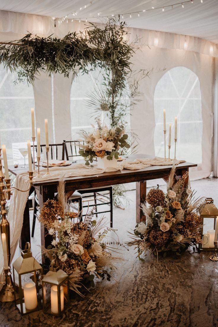 a table with candles, flowers and greenery is set up for a wedding reception