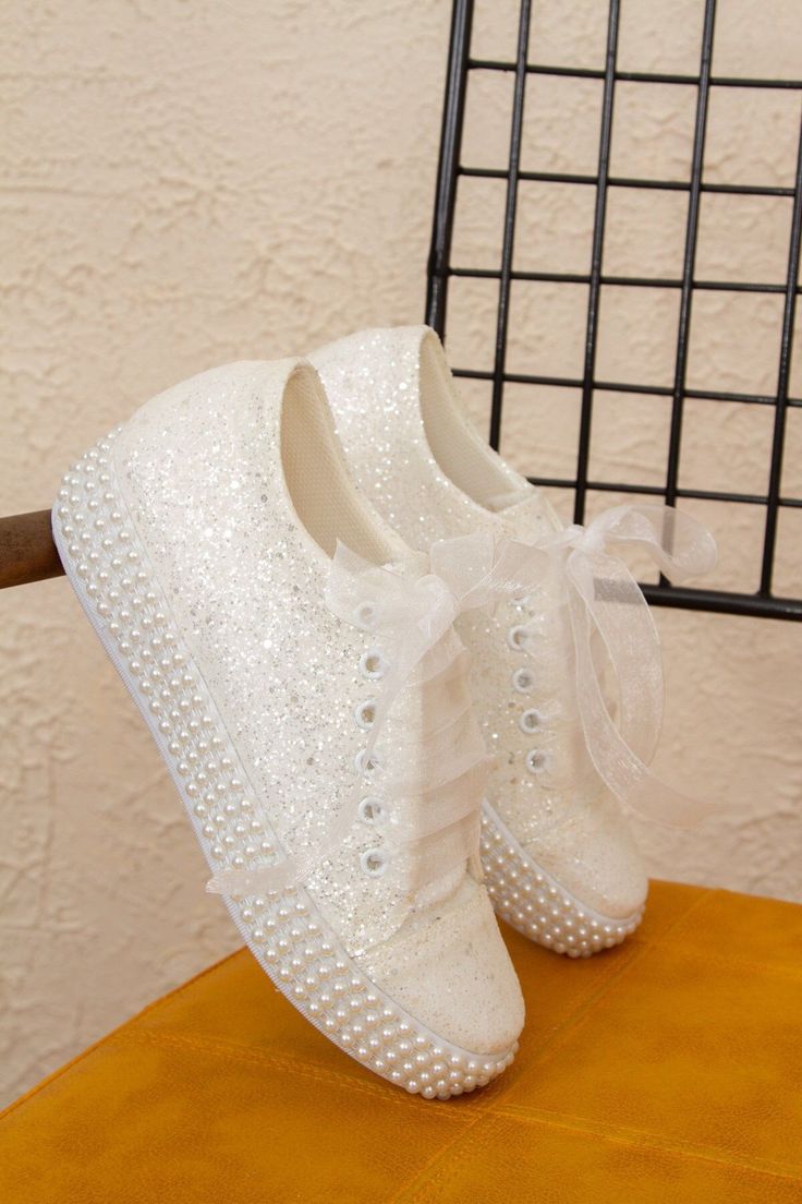 a pair of white shoes with pearls on them