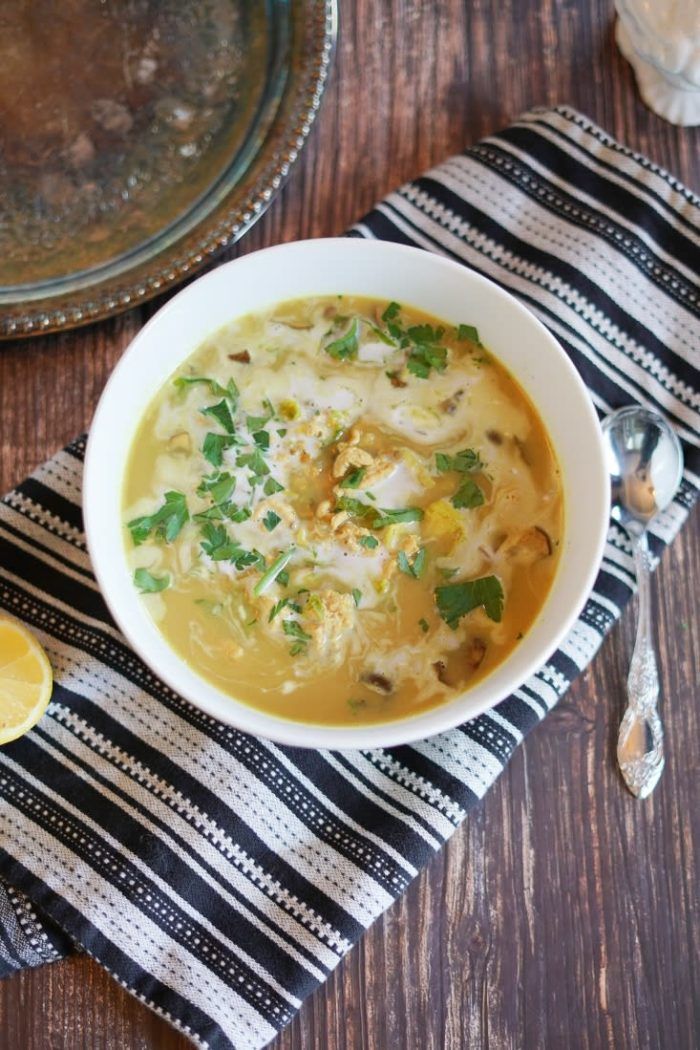 a white bowl filled with soup on top of a wooden table next to a spoon