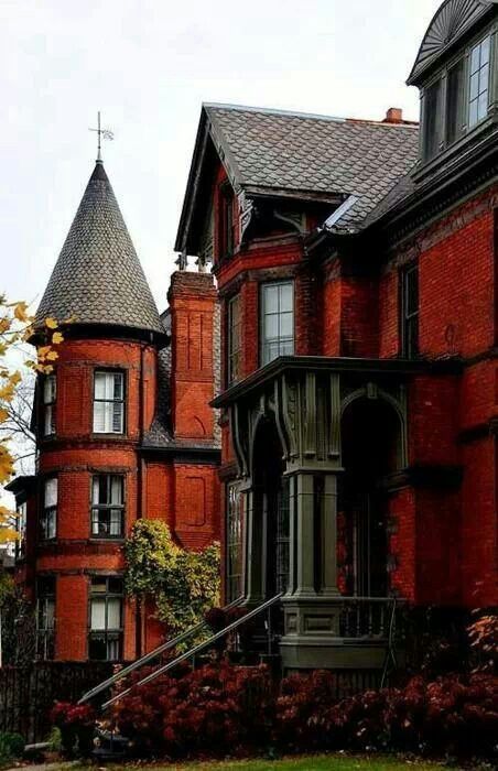 an old red brick house with steeples on it's roof and stairs leading up to the second floor