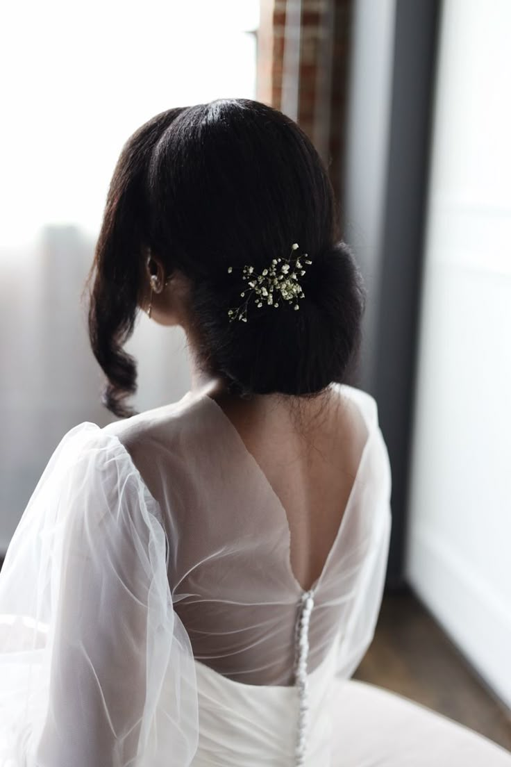 the back of a woman's head wearing a bridal hair comb with pearls on it