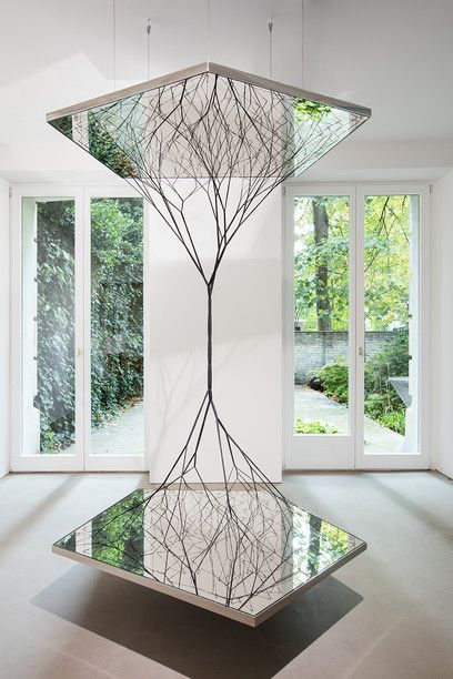 a glass table in the middle of a room with large windows and trees on it