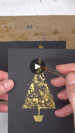 someone using scissors to cut out a christmas tree card with gold glitter on black paper