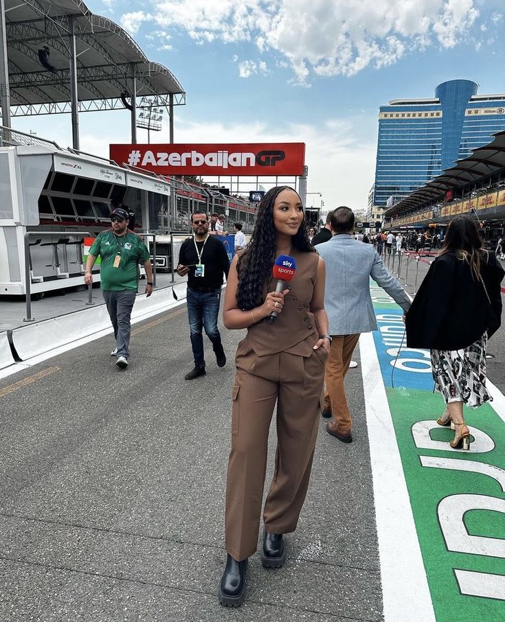 a woman with long hair is standing in the middle of a race track while holding a microphone