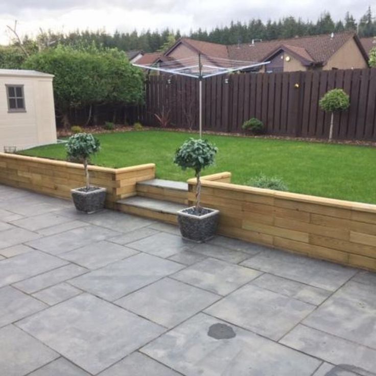 an outdoor patio with stone steps and planters in the center, surrounded by green grass