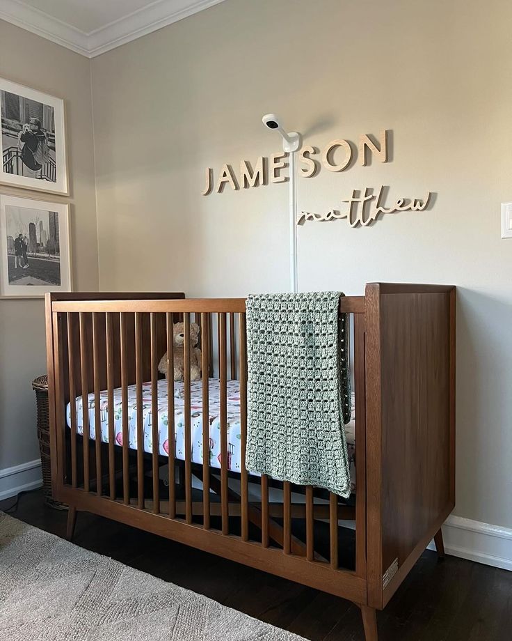 a baby's crib in the corner of a room with pictures on the wall