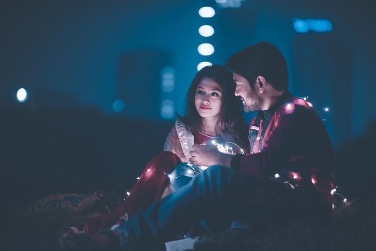 a man and woman sitting on the ground at night