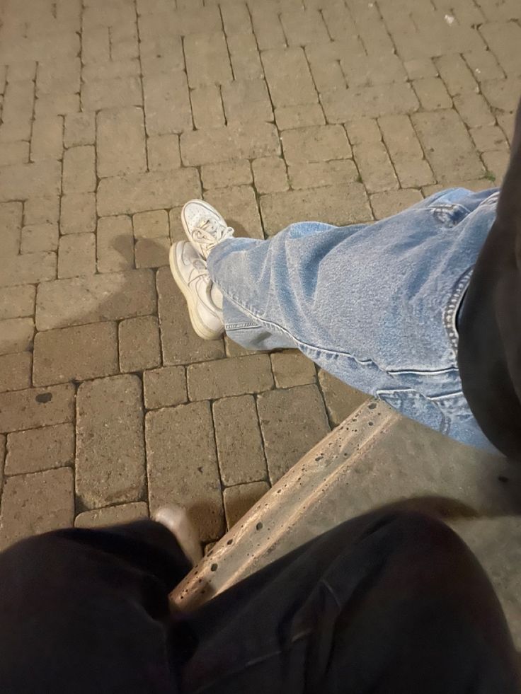 a person sitting on a bench with their feet propped up against the ground and one foot in the air