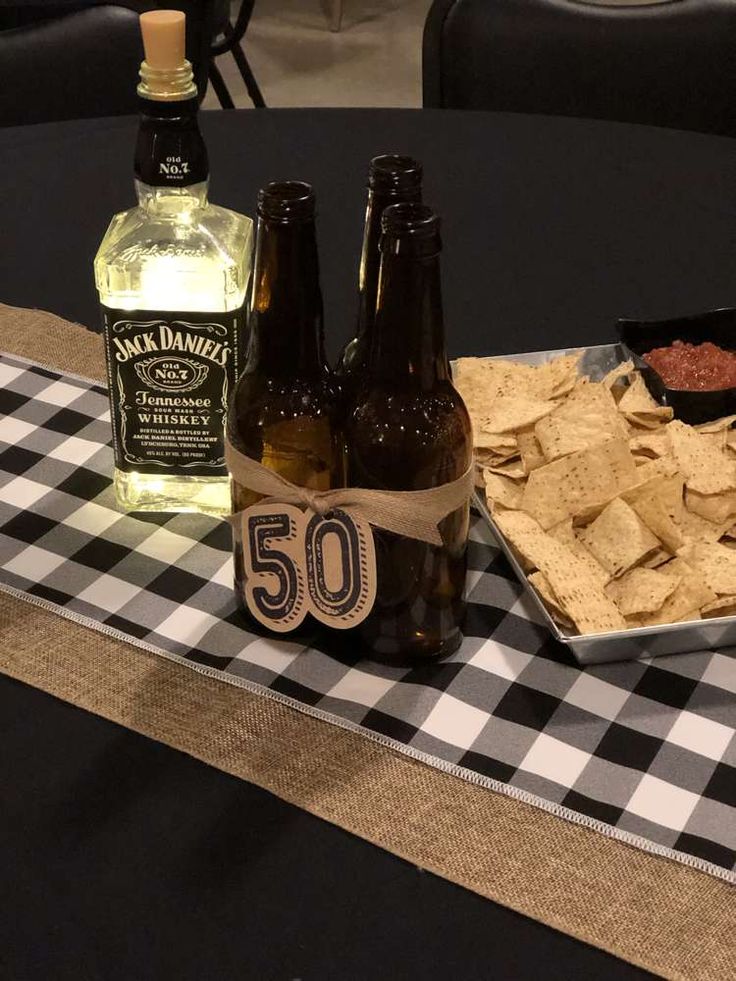 two bottles of beer and some chips on a table with a gingham cloth