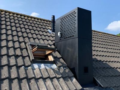 a chimney on top of a roof with a skylight in the corner and an open window above it