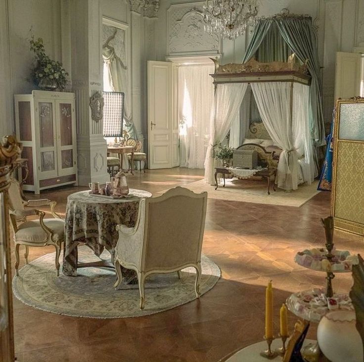 an ornately decorated living room with chandelier and table in the center, surrounded by antique furniture