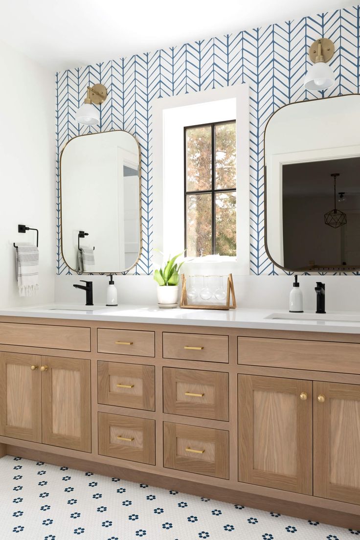 a bathroom with two sinks, mirrors and a large mirror on the wall above it