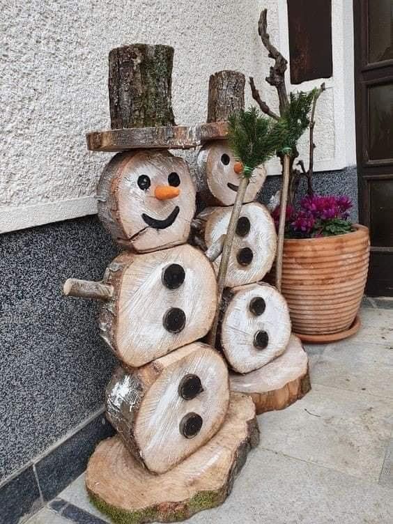 a snowman made out of logs sitting next to a potted plant