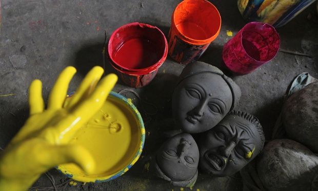 there are some clay faces on the ground next to paint cups and a yellow hand