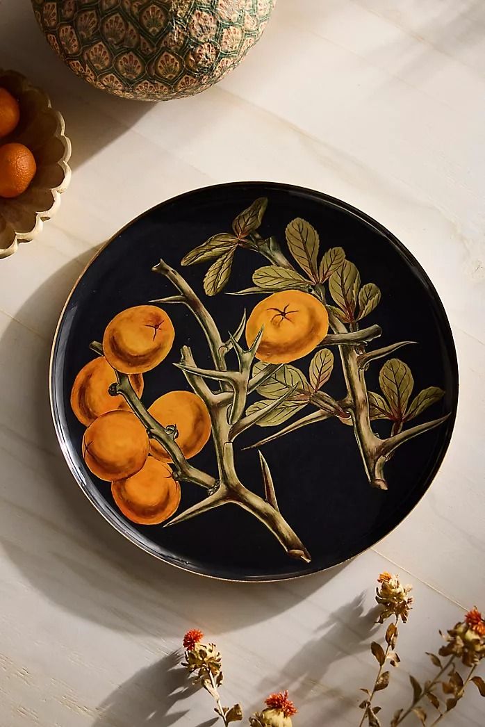 a black plate with oranges painted on it