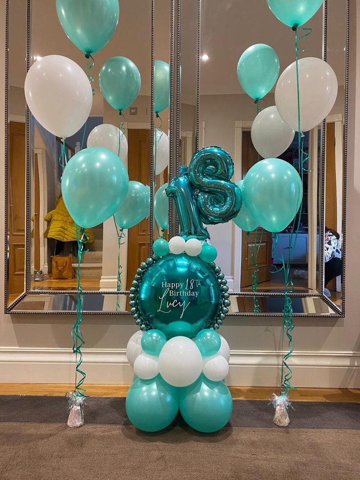 blue and white balloons are floating in front of a mirror