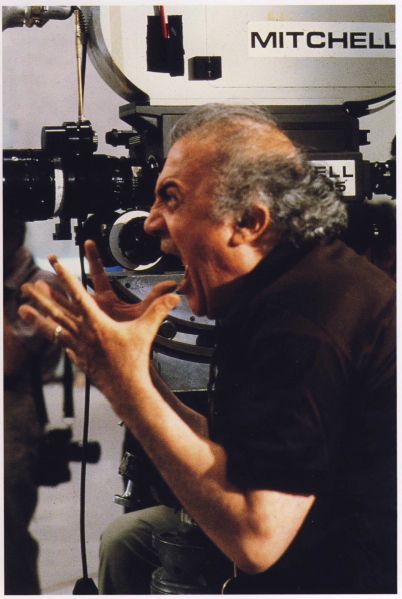 a man sitting in front of a camera on top of a tripod with his hands out