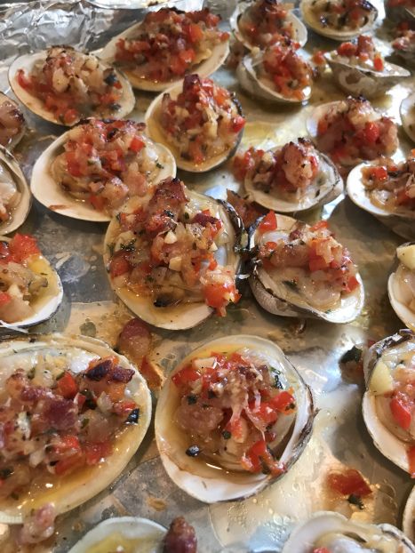 several open oysters with various toppings sitting on top of a metal tray covered in tin foil