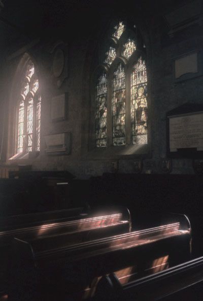 two stained glass windows in an old church with pews at the front and back