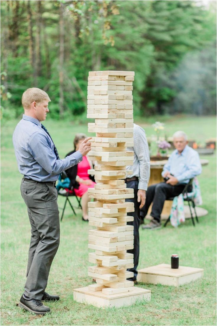 a man standing next to a giant wooden block tower