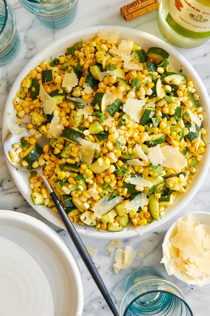 corn salad with parmesan cheese and herbs in a white bowl on a marble table