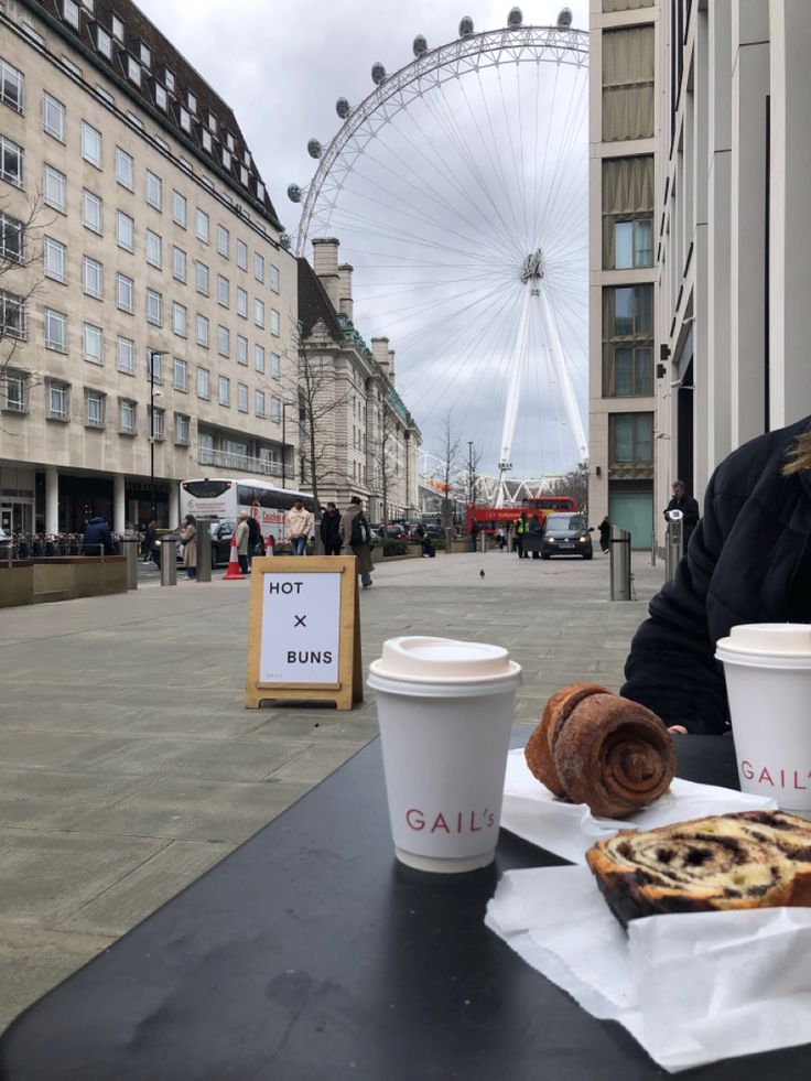 a woman sitting at a table with two cups of coffee and pastries in front of her