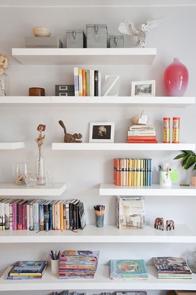 several white shelves with books and vases on them