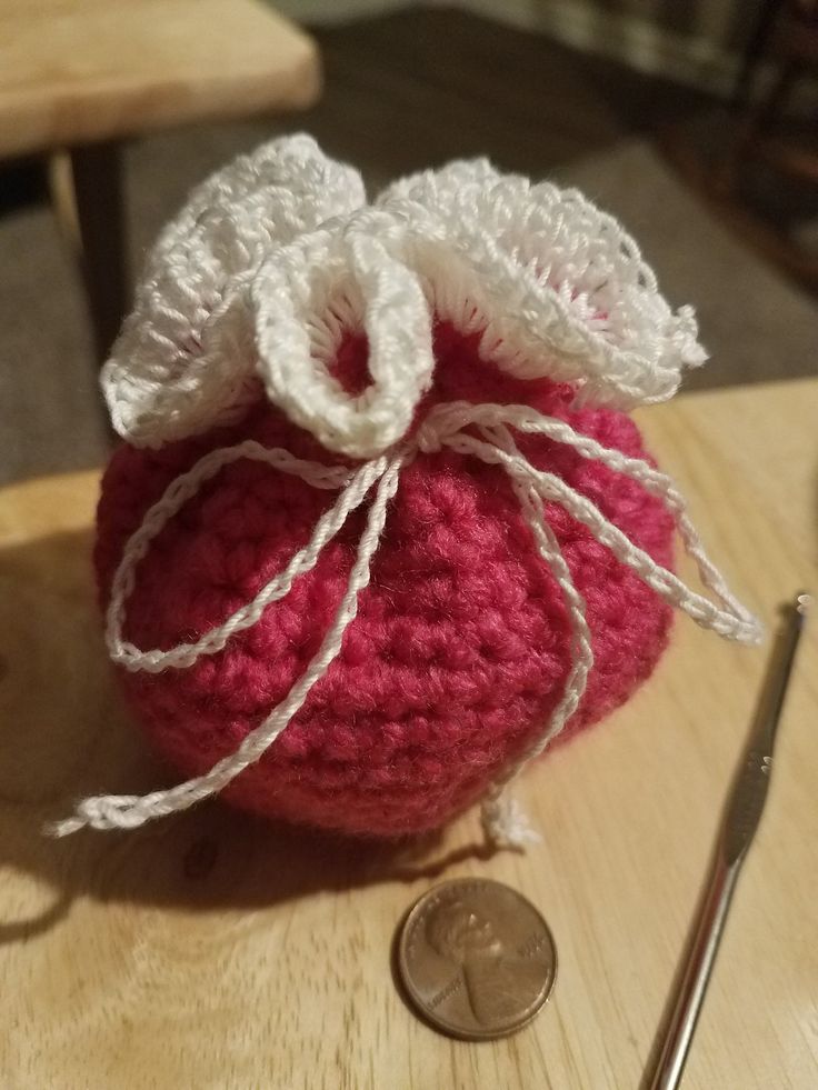 a crocheted bag sitting on top of a wooden table next to a coin