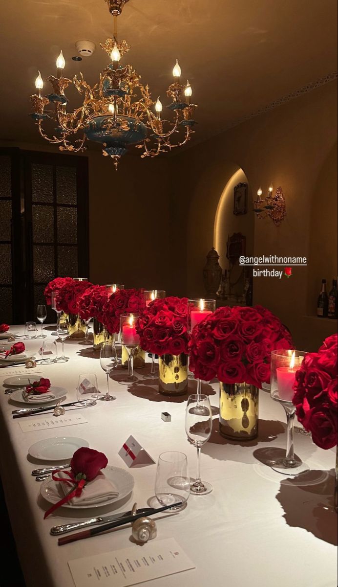 a long table is set with red roses and candles