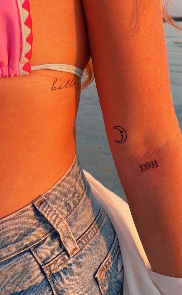 two women with matching tattoos on their arms, one is holding the other's arm