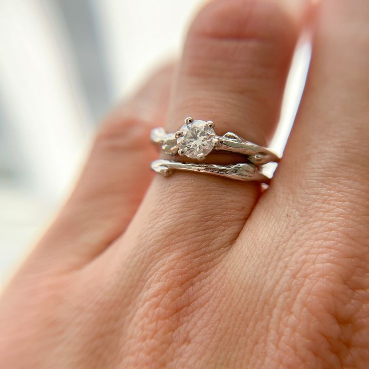 a close up of a person's hand with a diamond ring on their finger