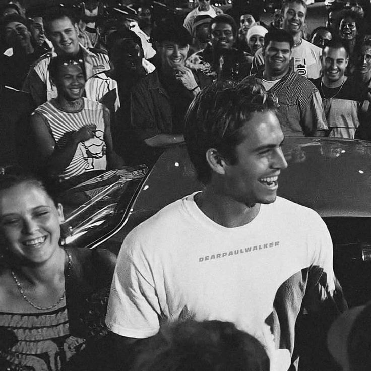 black and white photograph of a man smiling in front of a group of young people