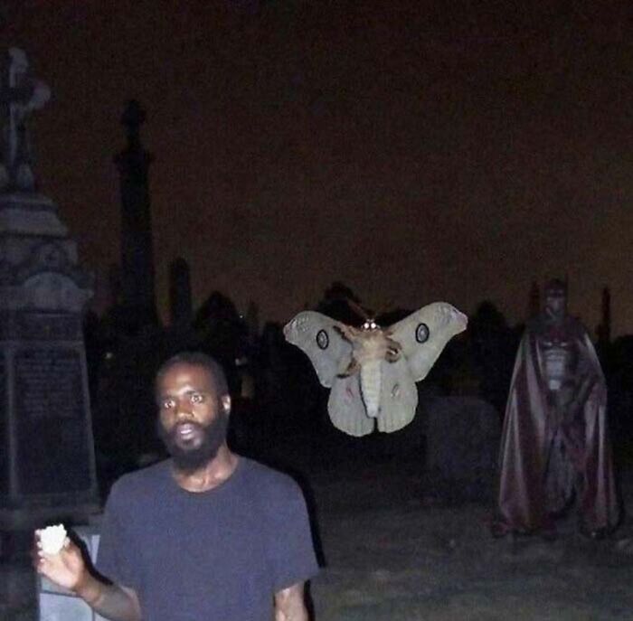 a man standing in front of a cemetery with a moth on it's back