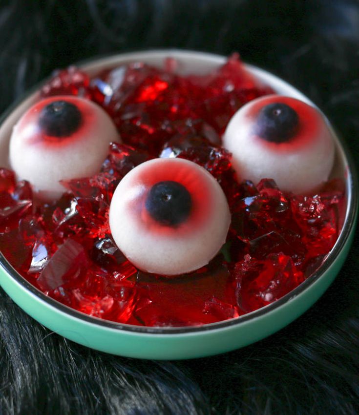 three fake eyes are in a bowl of red liquid