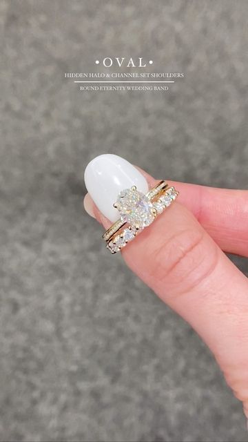 a woman's hand holding a ring with two stones on it and the middle finger