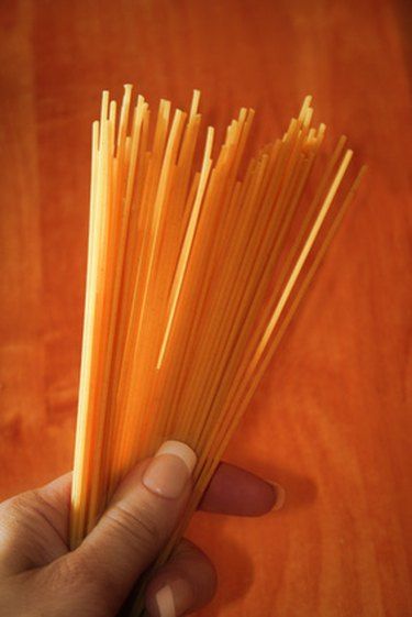 a hand is holding some noodles on a wooden table