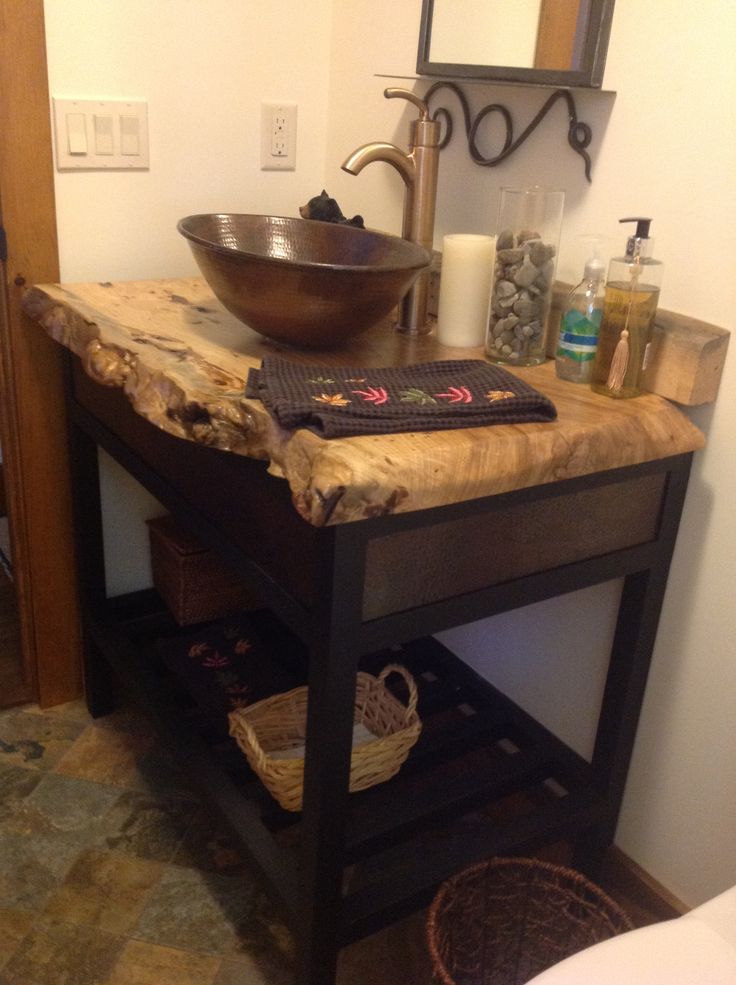 a wooden table with a bowl on top and baskets under it in front of the sink