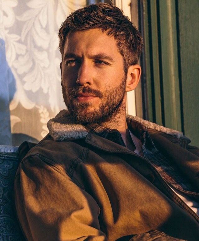 a man with a beard is sitting on a chair and looking off into the distance