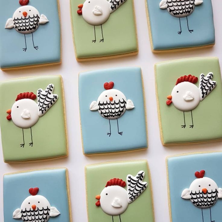 six decorated cookies in the shape of roosters on blue, green and white squares