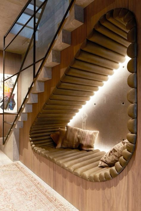 a curved wooden staircase with pillows on the bottom and an upturned bench below