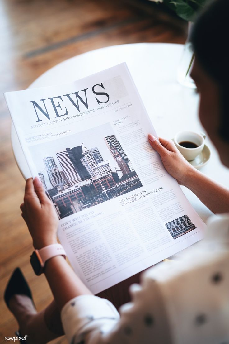 a woman reading a news paper on top of a table