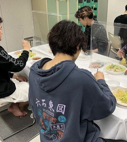 several people sitting at a table with plates of food in front of them and one person standing up