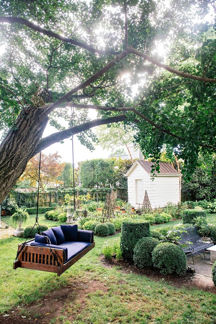 a wooden swing hanging from the side of a tree next to a lush green field