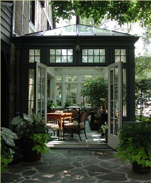 an enclosed patio with table, chairs and potted plants