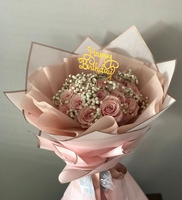 a bouquet of pink roses is sitting on top of a white box with the words happy birthday written on it