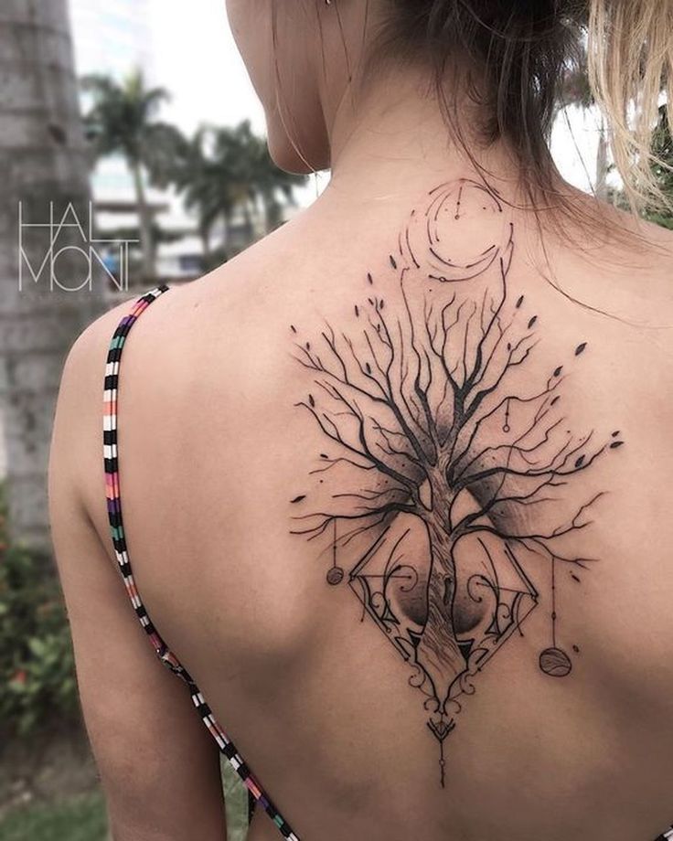 the back of a woman's neck with an intricate tree tattoo on her left shoulder