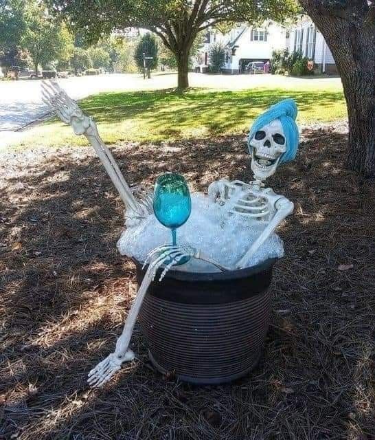 a skeleton in a tub with two blue glass goblets sitting on top of it