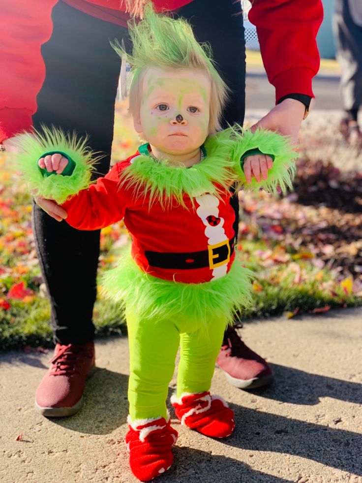 a small child dressed up as the grinch is being held by someone's hand